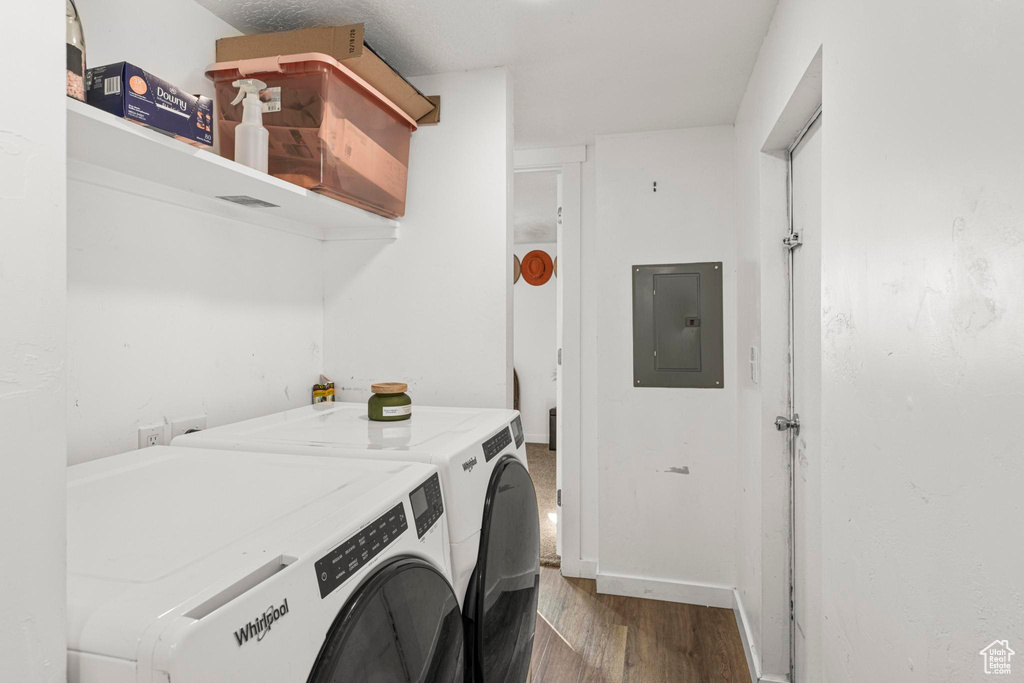 Clothes washing area featuring washing machine and clothes dryer, dark wood-type flooring, and electric panel