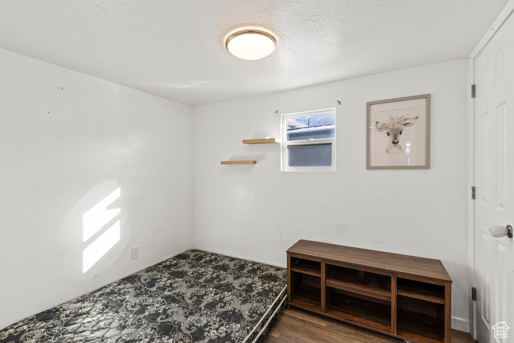 Unfurnished room featuring a textured ceiling and dark hardwood / wood-style flooring