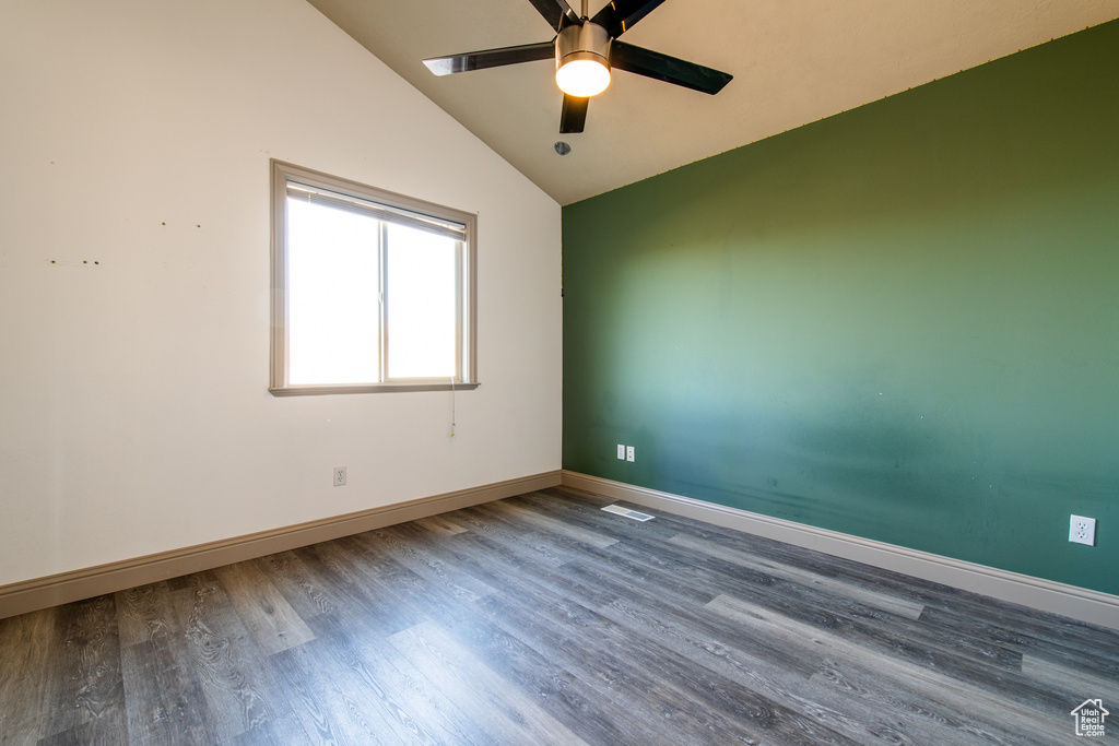 Empty room featuring hardwood / wood-style flooring, ceiling fan, and vaulted ceiling
