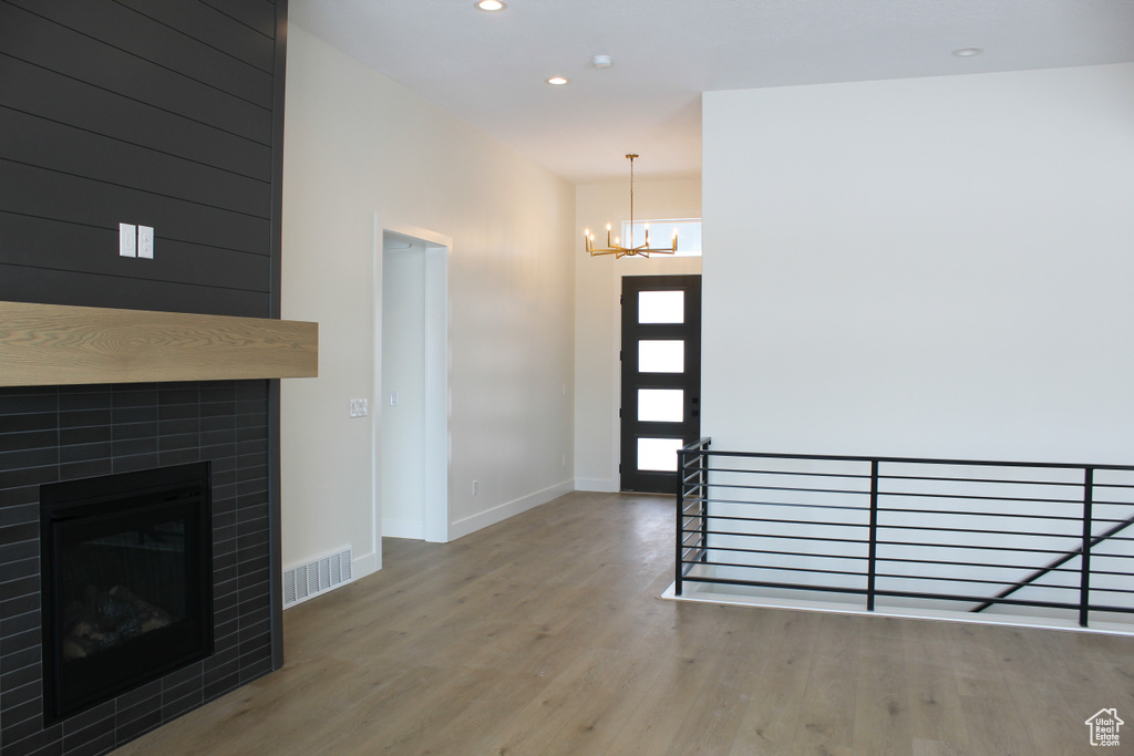Entrance foyer featuring a tiled fireplace, hardwood / wood-style floors, and an inviting chandelier