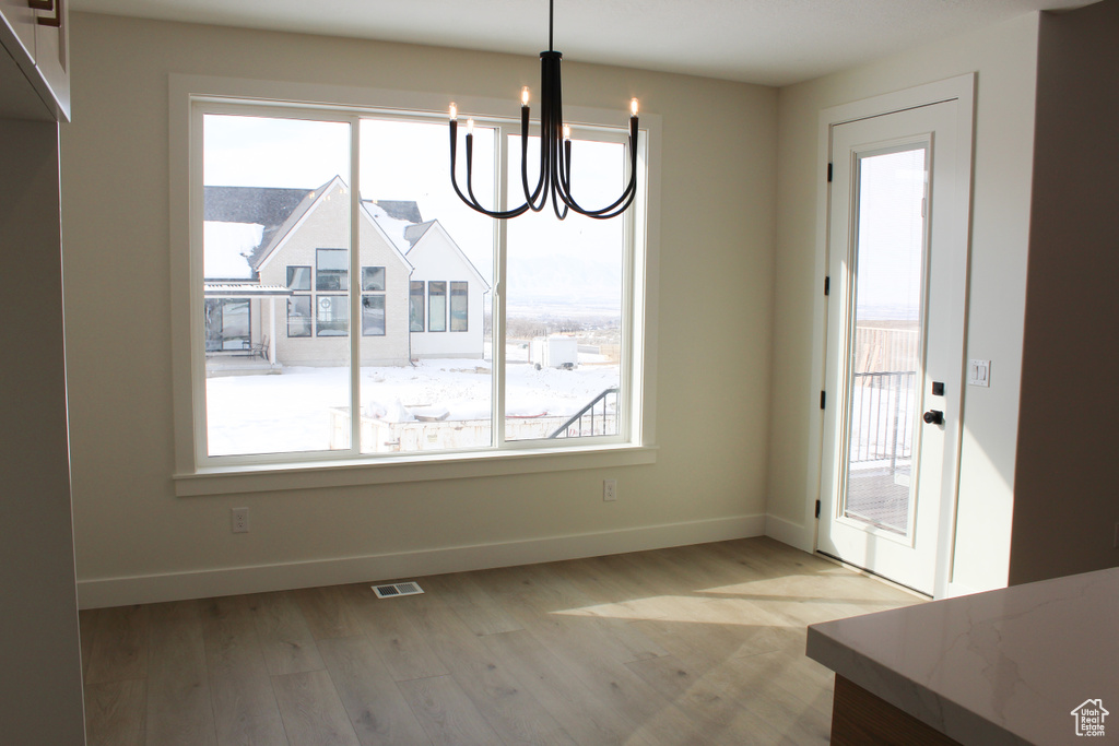 Unfurnished dining area with a chandelier and light wood-type flooring