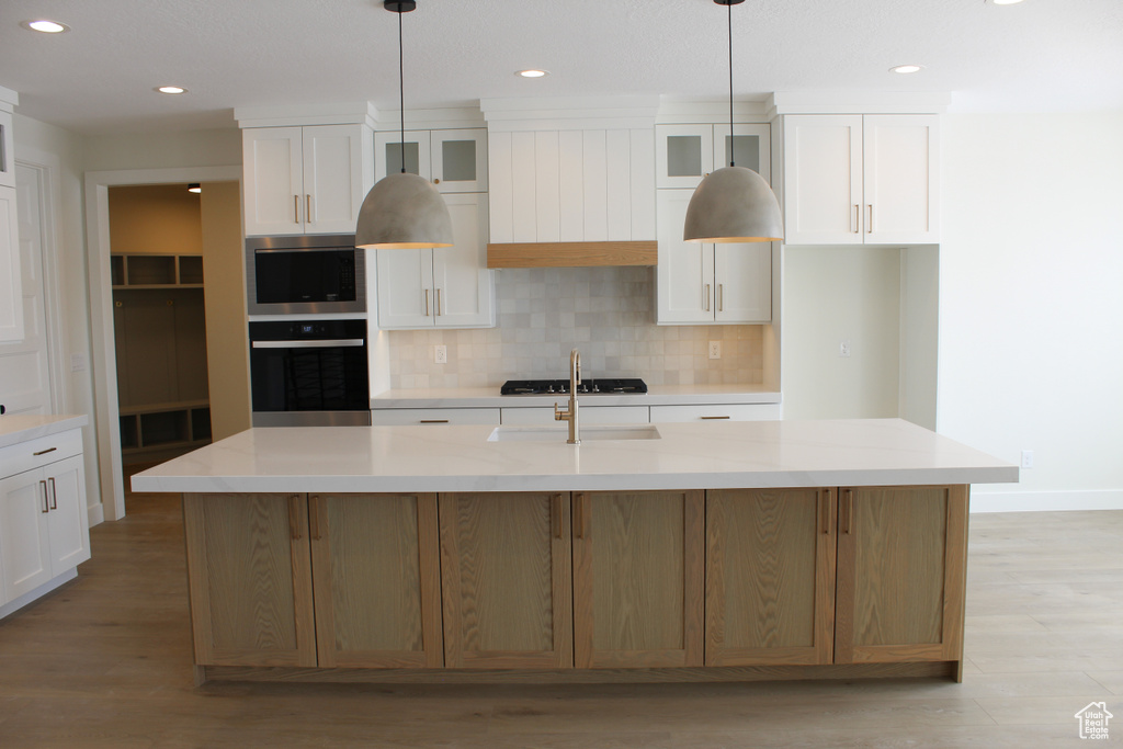 Kitchen with white cabinetry, a large island, pendant lighting, and black appliances
