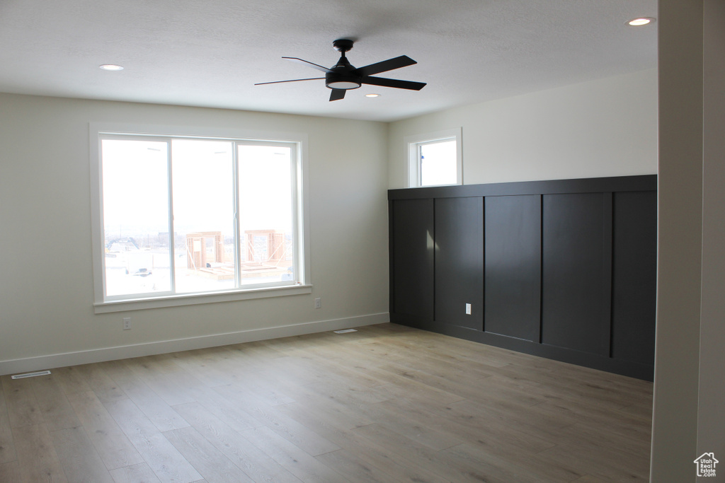 Unfurnished bedroom featuring multiple windows, ceiling fan, and light hardwood / wood-style floors
