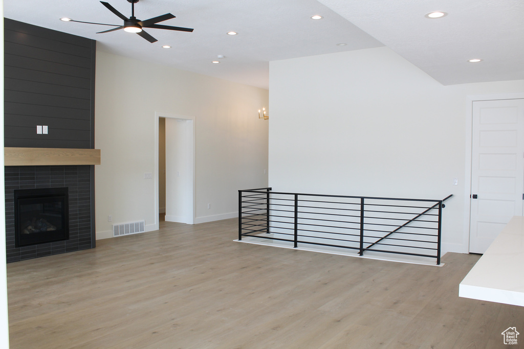 Unfurnished living room featuring a tile fireplace, ceiling fan, and light hardwood / wood-style flooring