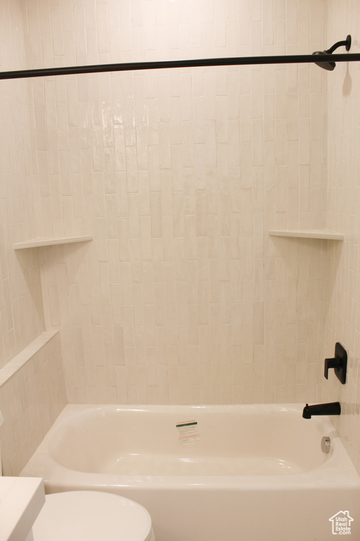 Bathroom with tiled shower / bath and toilet