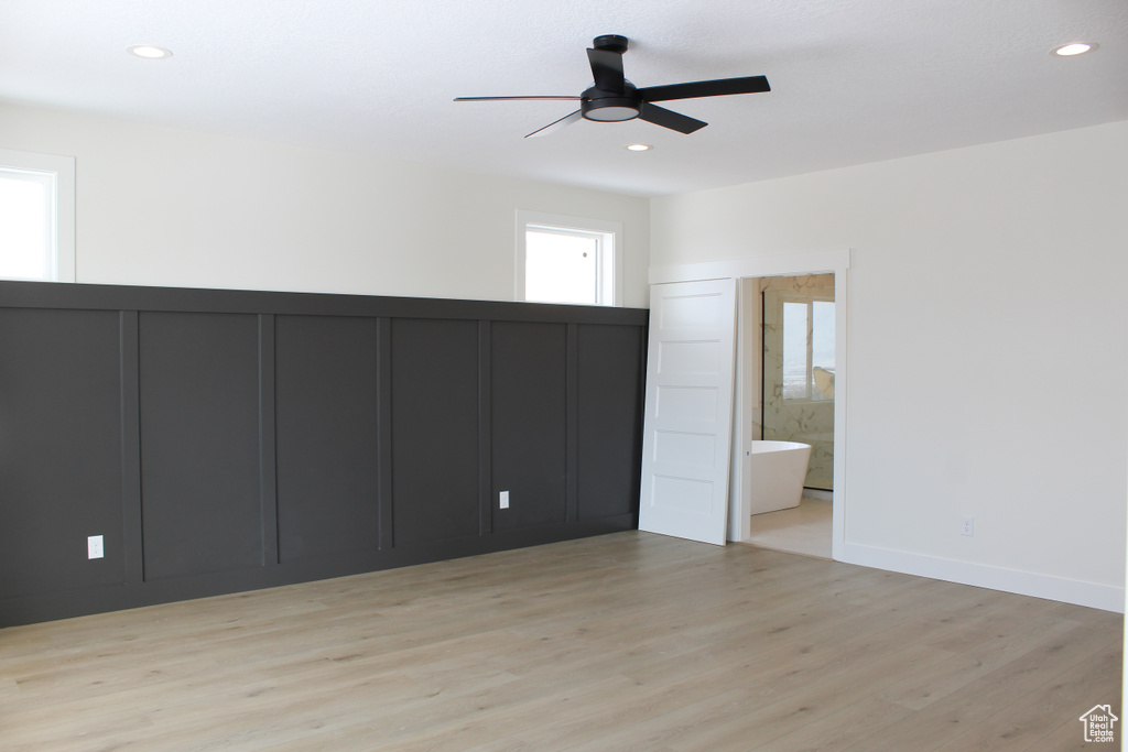 Unfurnished bedroom featuring multiple windows, light hardwood / wood-style flooring, ceiling fan, and ensuite bathroom