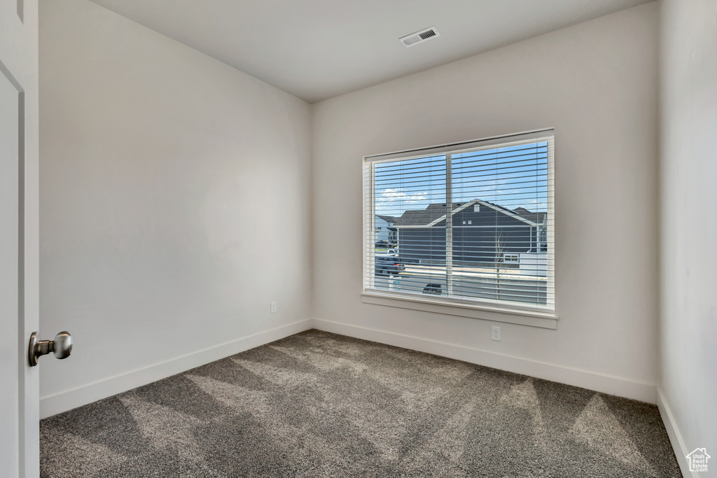 Carpeted spare room featuring baseboards