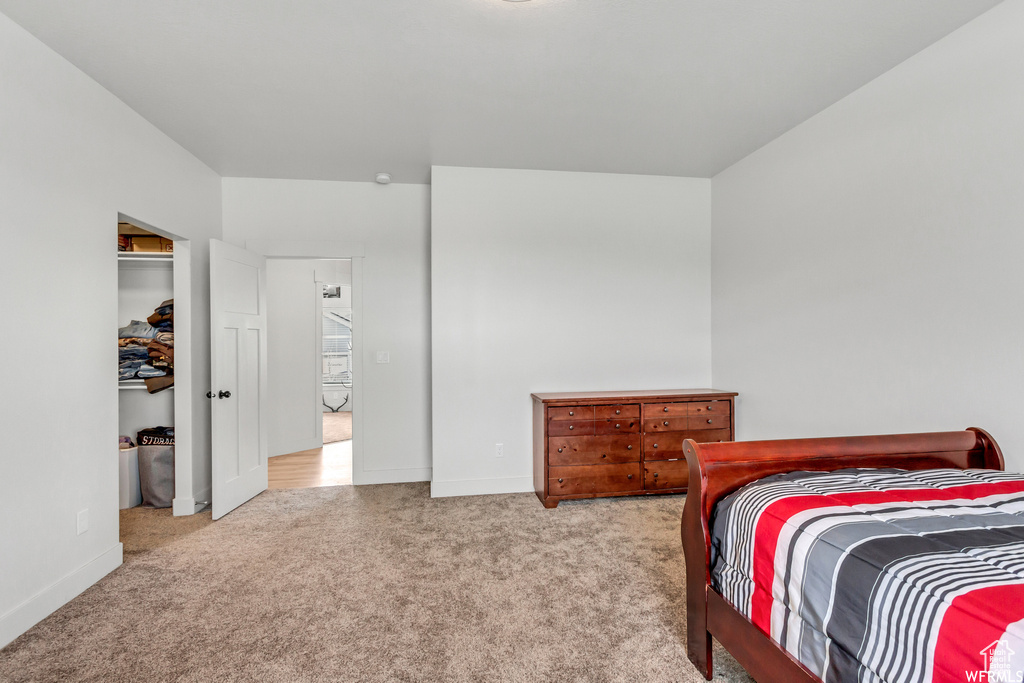 Bedroom with light colored carpet and a closet