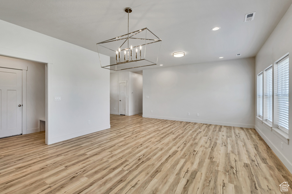 Empty room with light wood-style floors, baseboards, a chandelier, and recessed lighting
