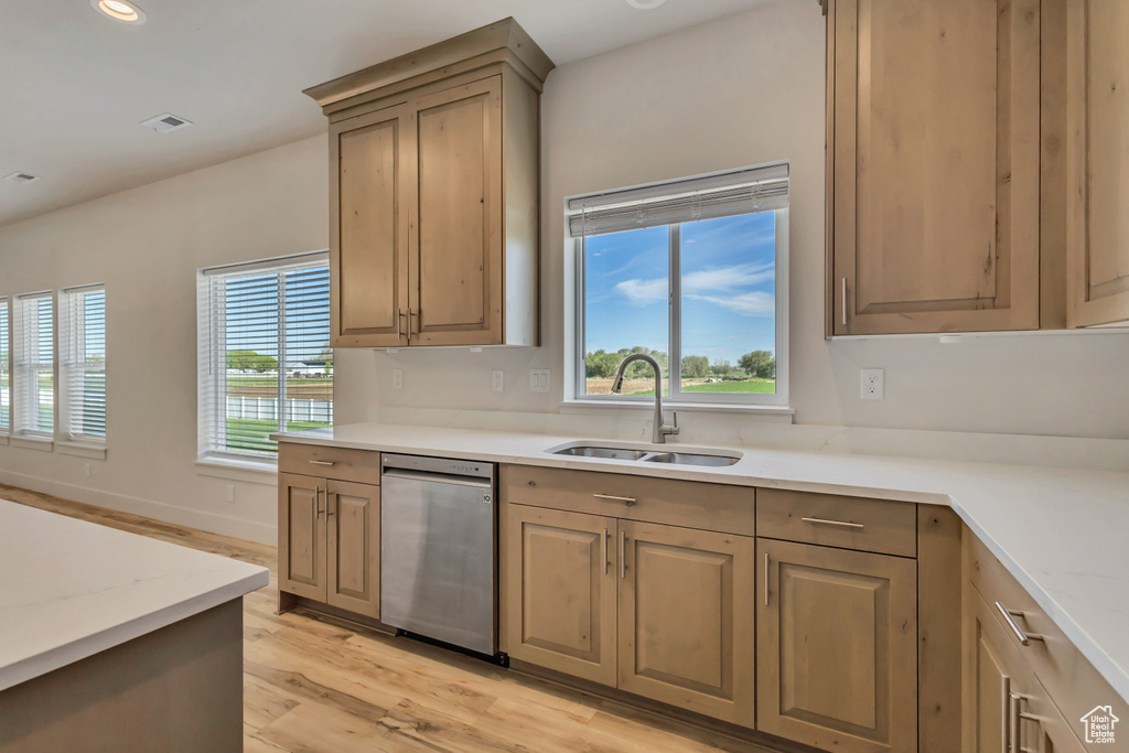 Kitchen featuring dishwasher, a sink, light wood-style flooring, recessed lighting, and light stone countertops