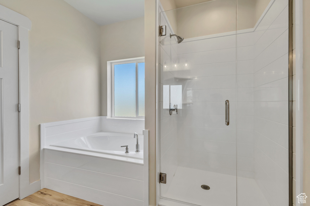 Bathroom with a shower stall, a bath, and wood finished floors