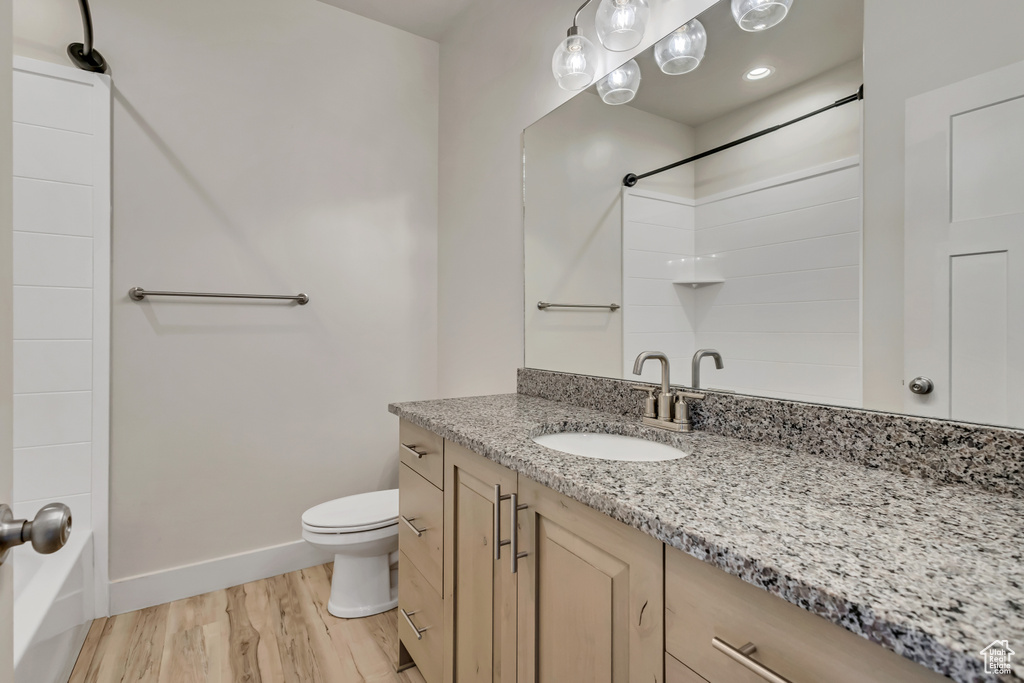 Full bath with wood finished floors, baseboards, toilet, vanity, and shower / tub combination