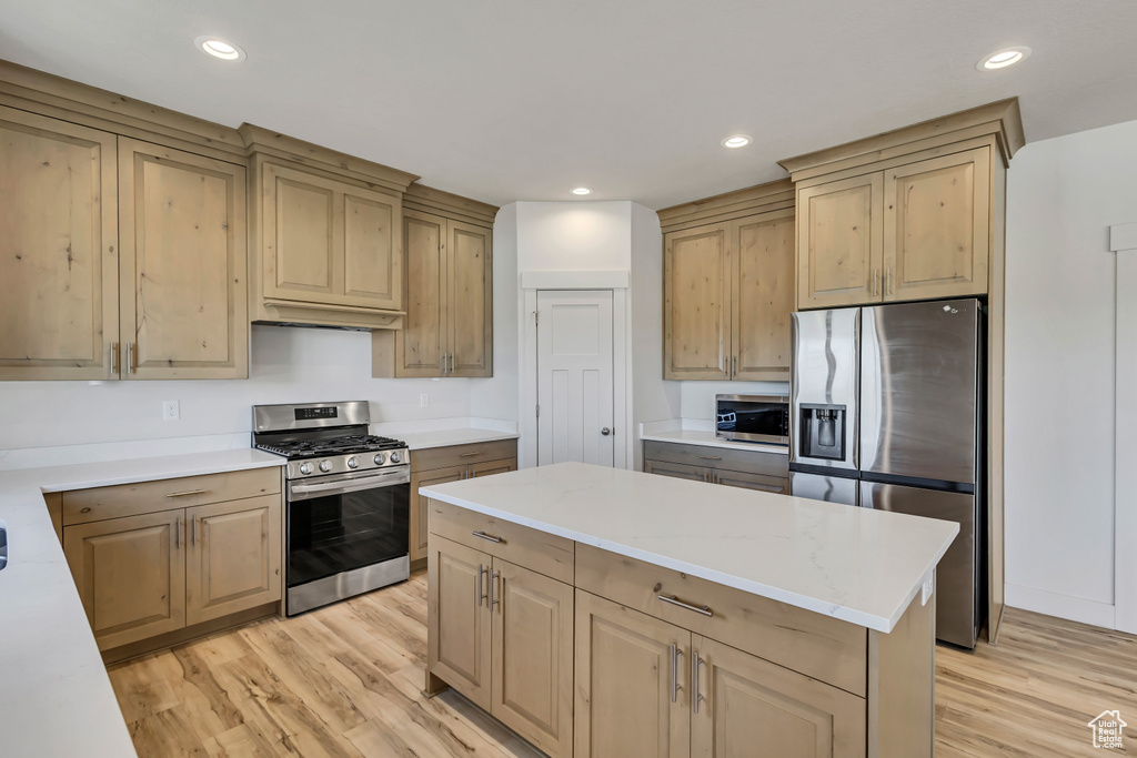 Kitchen with appliances with stainless steel finishes, light wood-style flooring, recessed lighting, a center island, and light brown cabinets