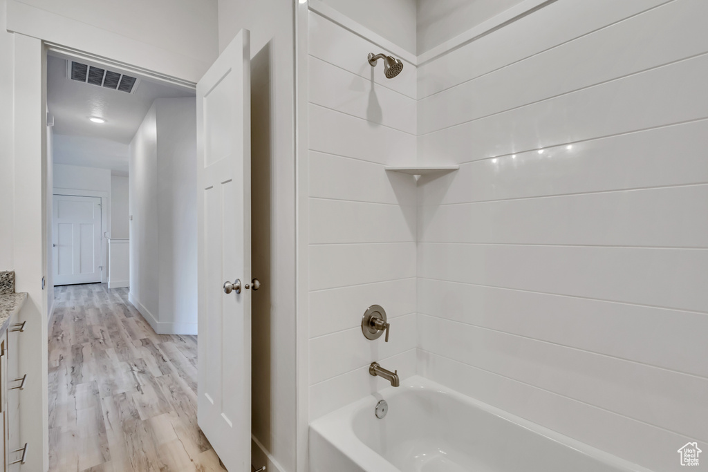 Bathroom with shower / washtub combination and wood finished floors