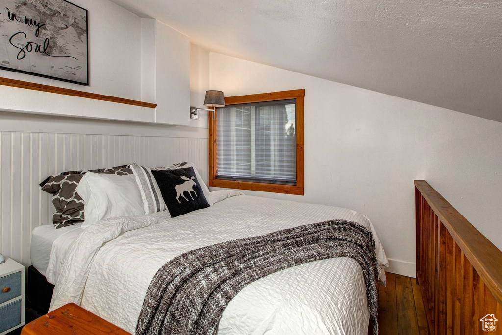 Bedroom featuring hardwood / wood-style flooring and vaulted ceiling