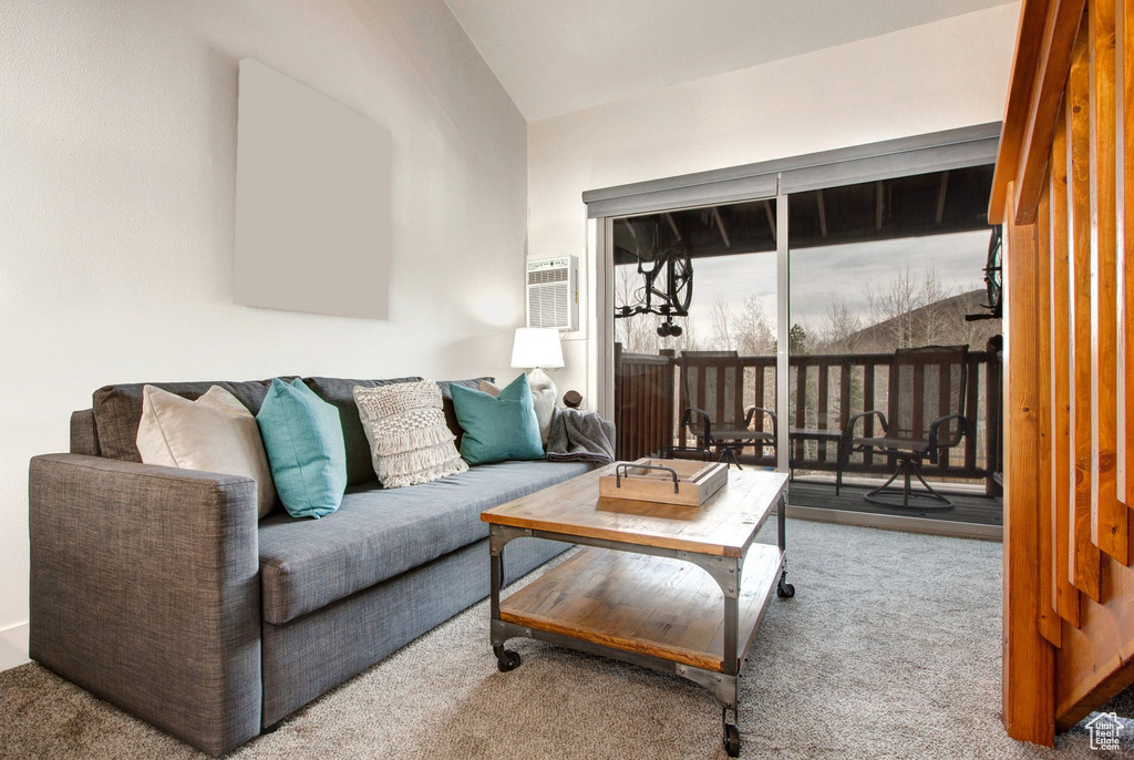 Carpeted living room with lofted ceiling and an AC wall unit