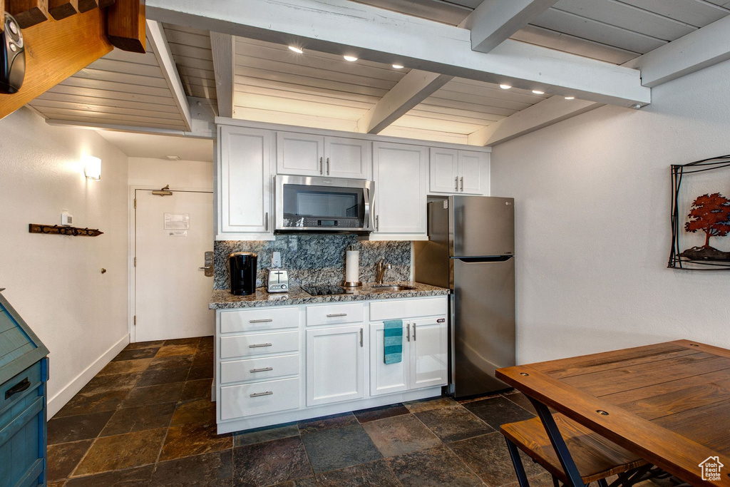 Kitchen featuring stainless steel appliances, light stone counters, wood ceiling, and beam ceiling