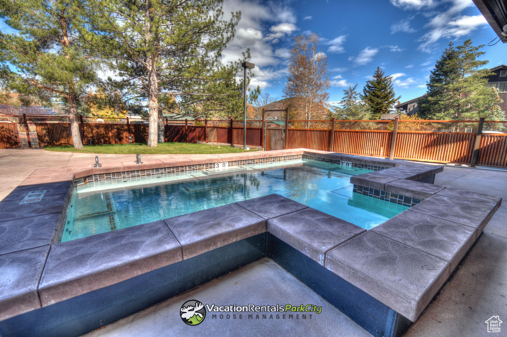 View of swimming pool featuring a hot tub and a patio