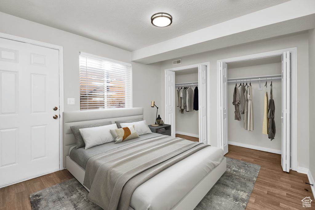 Bedroom featuring two closets and dark hardwood / wood-style floors