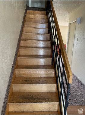 Staircase with hardwood / wood-style flooring and a textured ceiling