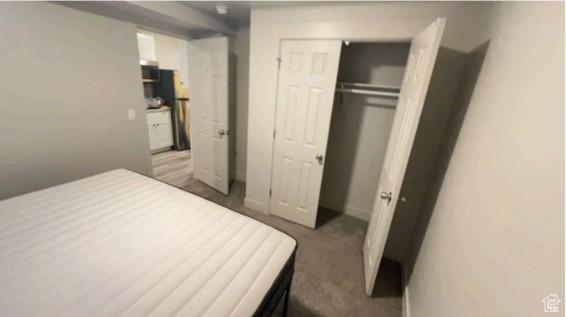 Bedroom with dark carpet, stainless steel fridge, and a closet