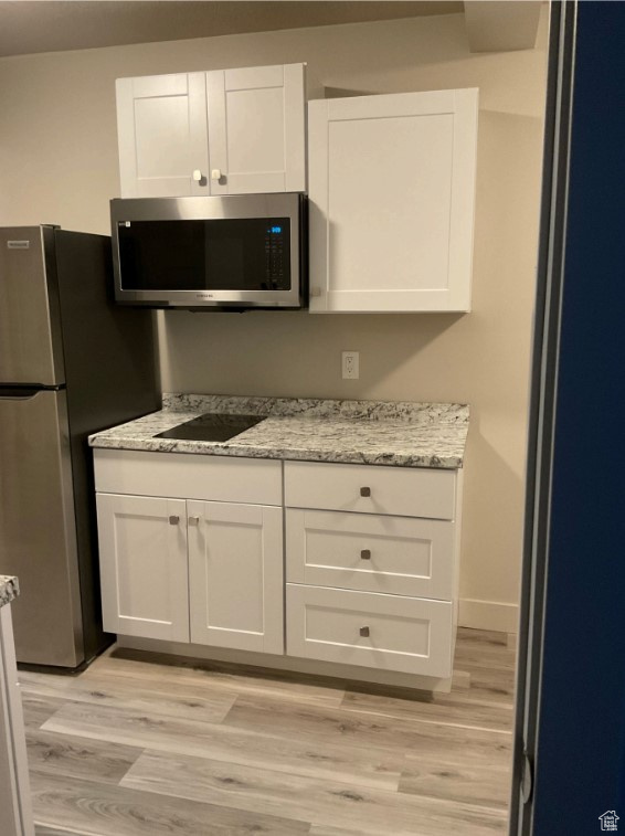 Kitchen featuring appliances with stainless steel finishes, light hardwood / wood-style flooring, and white cabinets