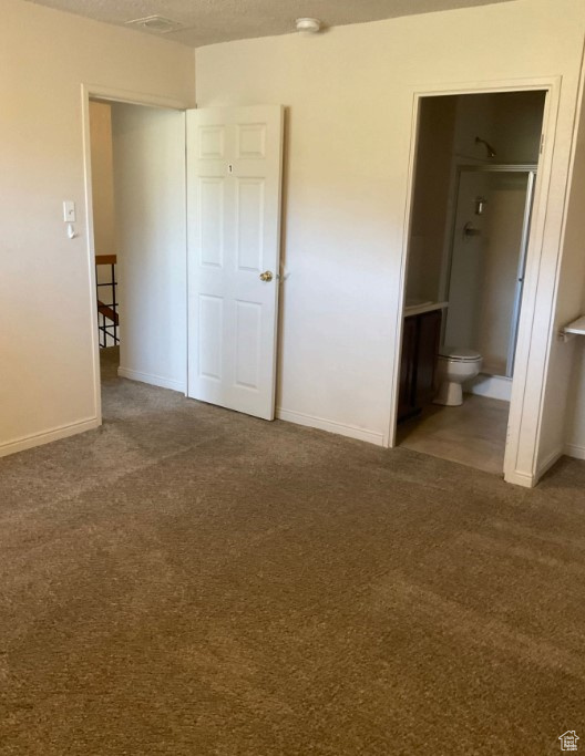 Unfurnished bedroom featuring ensuite bathroom and carpet