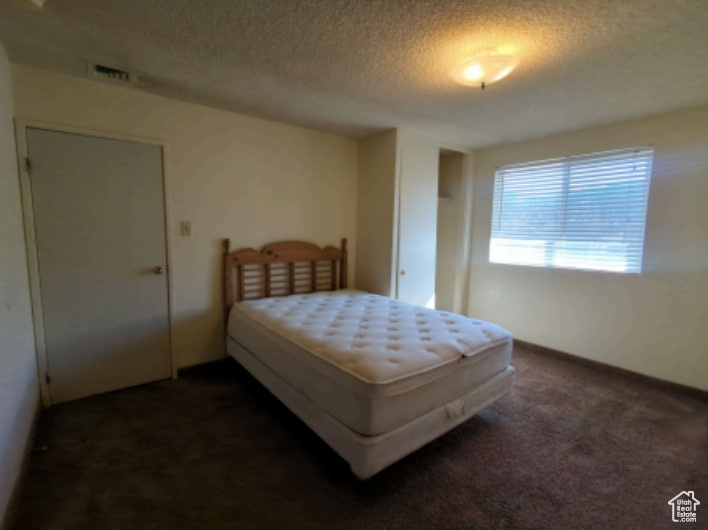 Carpeted bedroom featuring a textured ceiling