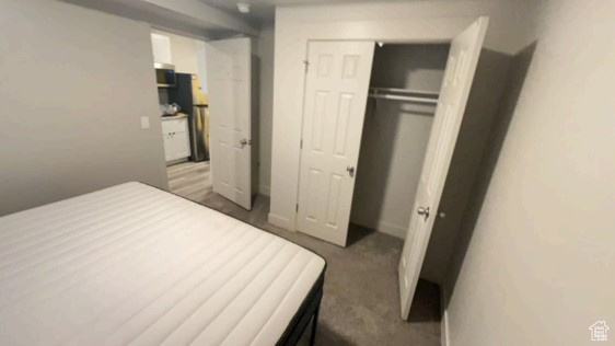 Carpeted bedroom with stainless steel refrigerator and a closet