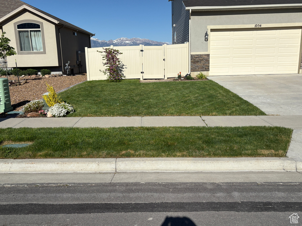 View of home\'s exterior with concrete driveway, a gate, stone siding, a garage, and a mountain view