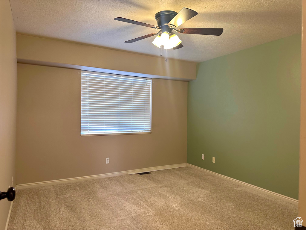 Unfurnished room with light carpet, ceiling fan, and a textured ceiling