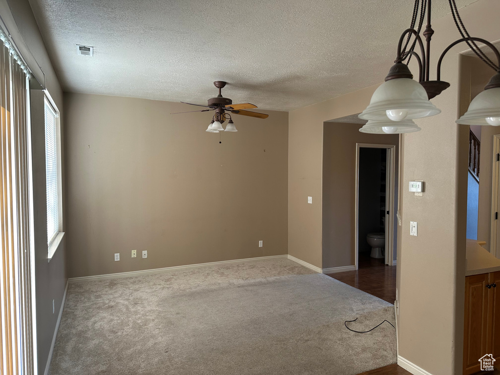 Carpeted spare room featuring ceiling fan and a textured ceiling