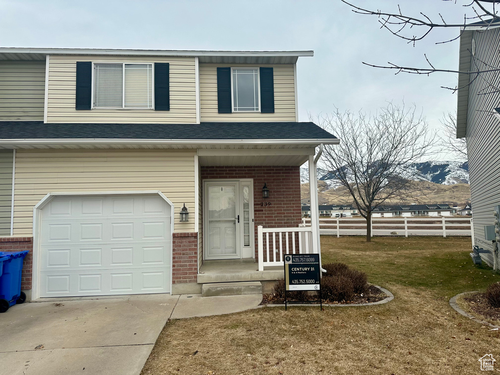 View of front of property with a mountain view, a garage, and a front lawn