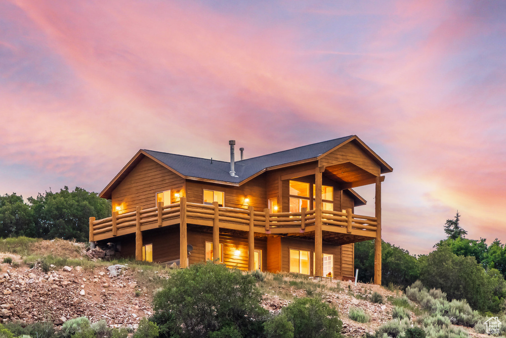 Back of property at dusk featuring a wooden deck