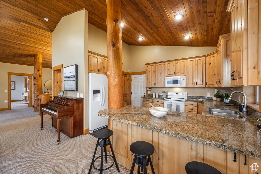Kitchen with white appliances, wood ceiling, a peninsula, light colored carpet, and high vaulted ceiling