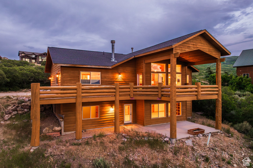 Rear view of property featuring a patio area and roof with shingles