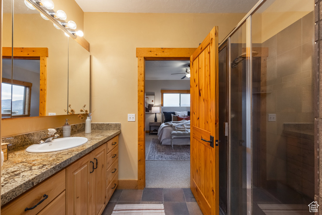 Ensuite bathroom featuring vanity, a shower stall, and ceiling fan
