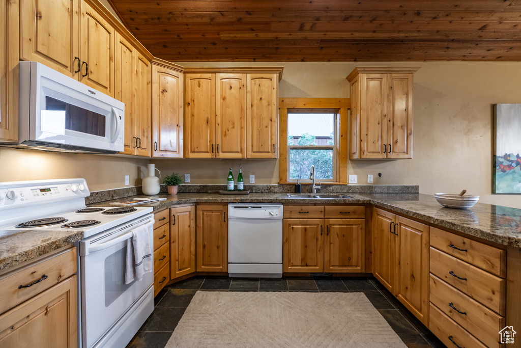 Kitchen featuring white appliances, wooden ceiling, a peninsula, light brown cabinetry, and dark tile patterned floors