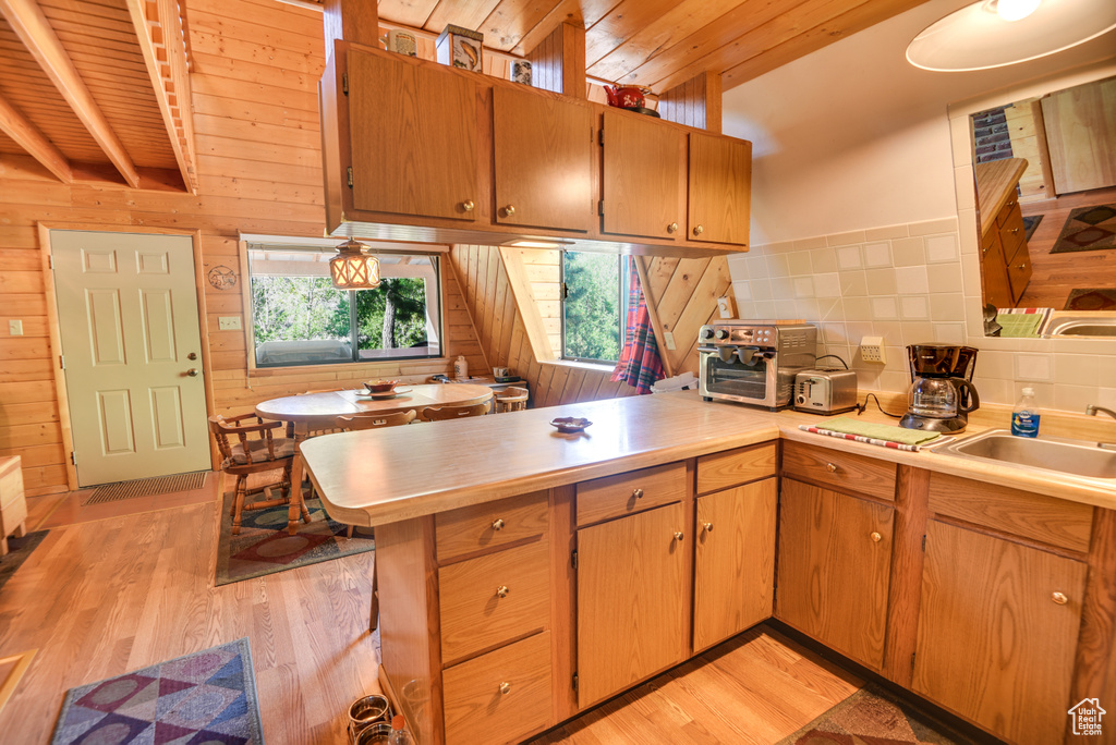 Kitchen with sink, light wood-type flooring, wooden ceiling, kitchen peninsula, and beam ceiling