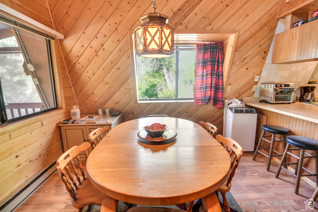 Dining room featuring a baseboard heating unit, light hardwood / wood-style floors, and wood walls