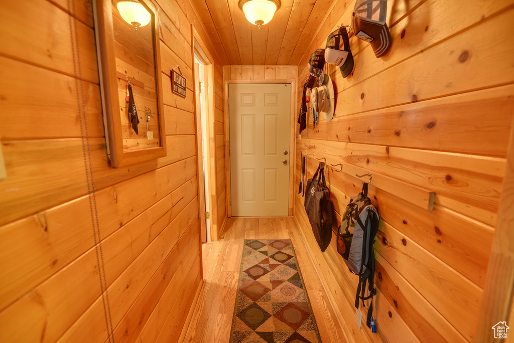 Hallway featuring light wood-type flooring, wood ceiling, and wood walls