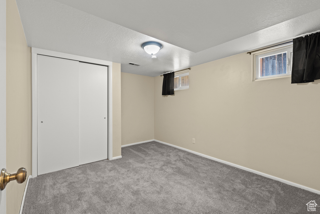 Below grade area with carpet, a textured ceiling, and baseboards