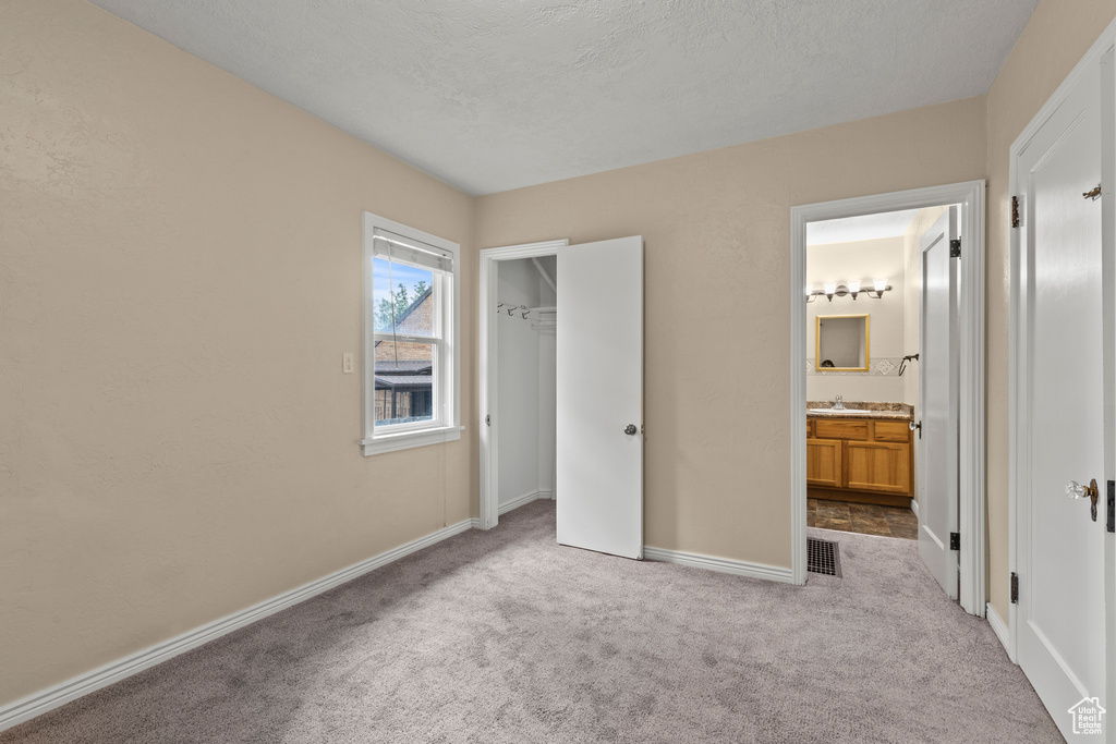 Unfurnished bedroom with carpet flooring, baseboards, ensuite bathroom, and a sink