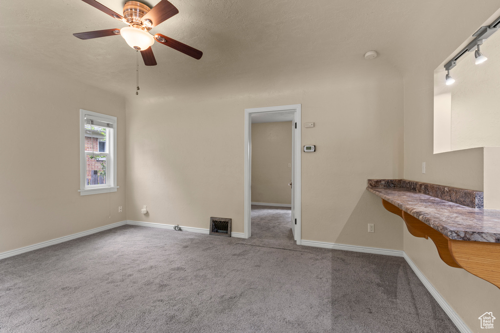 Carpeted spare room with a ceiling fan, baseboards, and a smoke detector