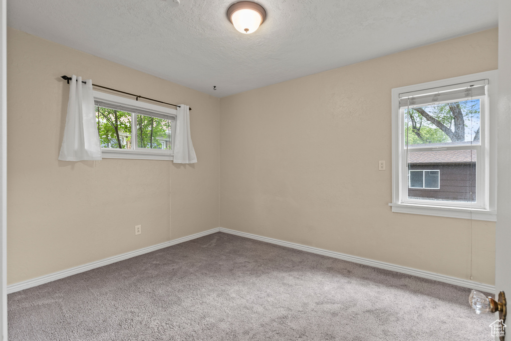 Carpeted spare room with a textured ceiling and baseboards