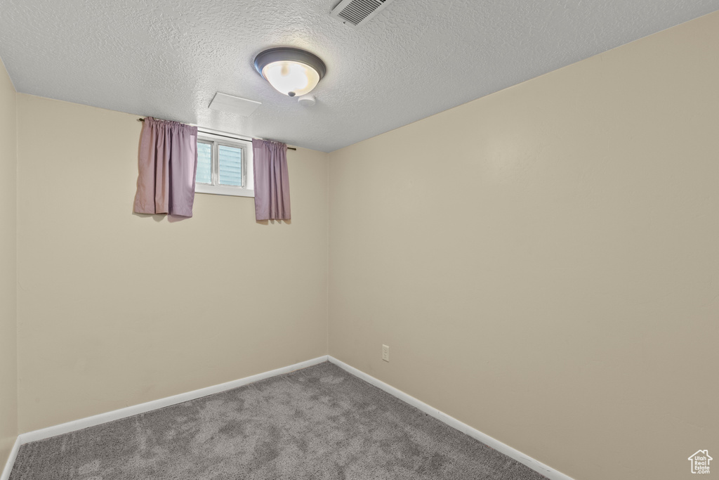 Carpeted spare room with baseboards and a textured ceiling
