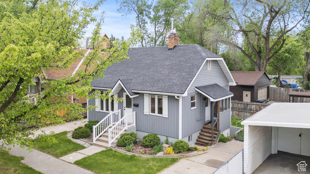 View of front of home with a shingled roof and a chimney