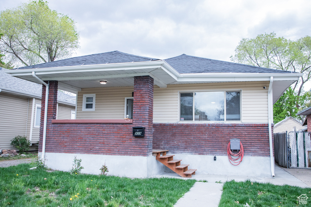 View of front of property featuring brick siding, fence, and roof with shingles
