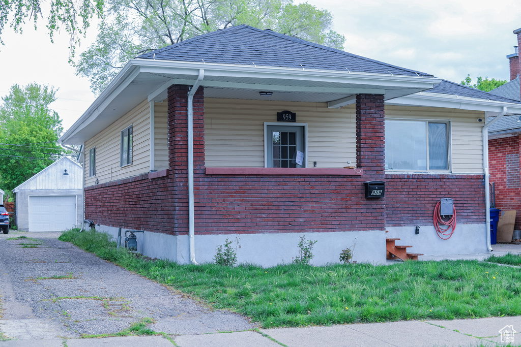 View of side of home with an outdoor structure, brick siding, a garage, and asphalt driveway