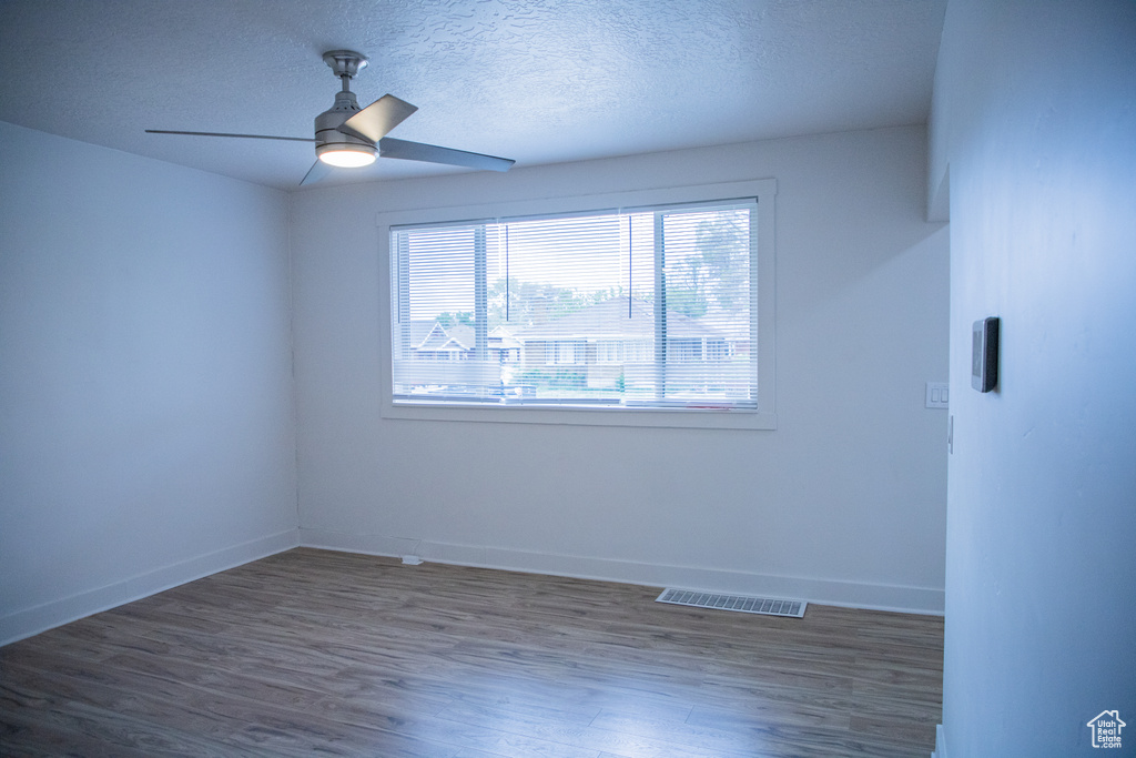 Unfurnished room with wood finished floors, baseboards, a textured ceiling, and a ceiling fan